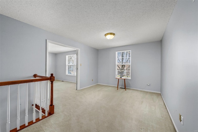 carpeted spare room with baseboards and a textured ceiling