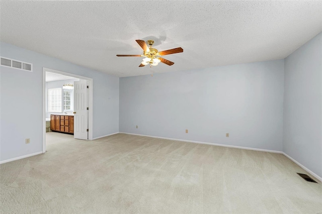 empty room with light carpet, visible vents, a textured ceiling, and ceiling fan