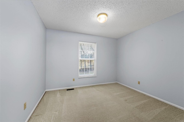 carpeted spare room featuring baseboards, visible vents, and a textured ceiling