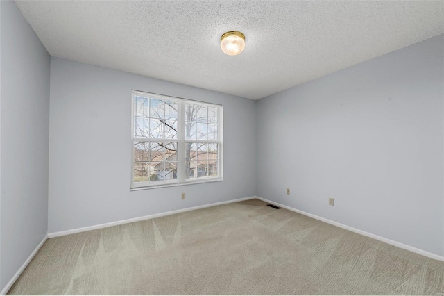 unfurnished room with a textured ceiling, carpet, visible vents, and baseboards