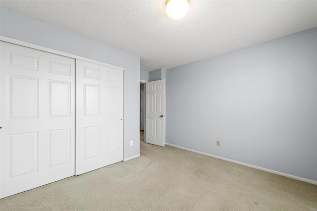 unfurnished bedroom with a closet, a textured ceiling, baseboards, and carpet floors