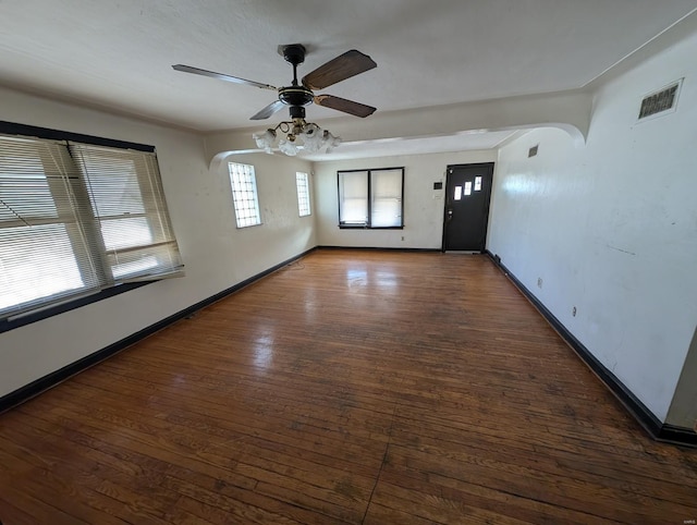 empty room with hardwood / wood-style floors, a ceiling fan, visible vents, and baseboards