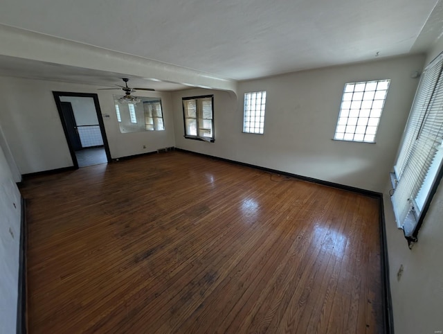 unfurnished room featuring dark wood-type flooring, a ceiling fan, baseboards, and visible vents