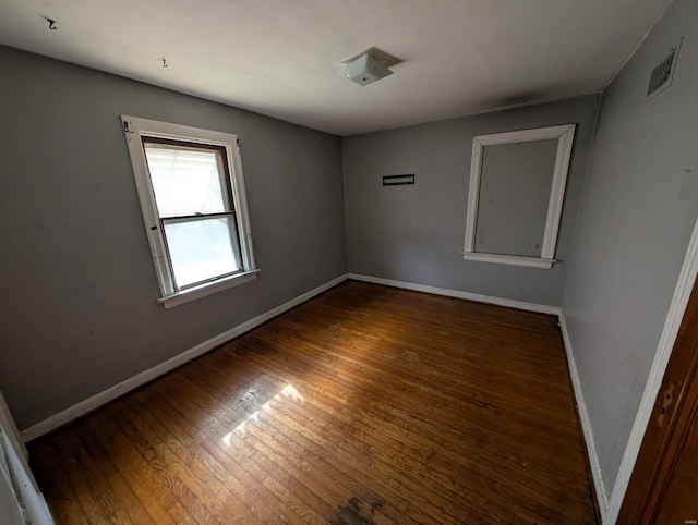 empty room with visible vents, baseboards, and wood-type flooring