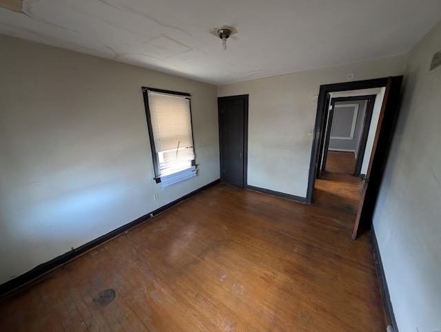 spare room with baseboards and wood-type flooring