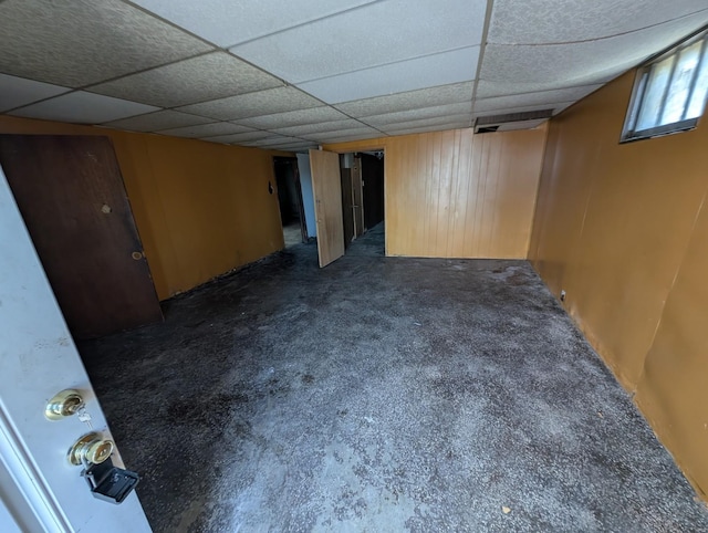 basement featuring a paneled ceiling and dark carpet