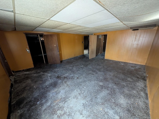 finished basement with wood walls, a paneled ceiling, and carpet floors