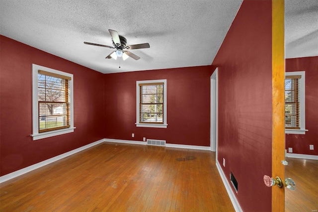 unfurnished room with visible vents, baseboards, ceiling fan, and hardwood / wood-style flooring