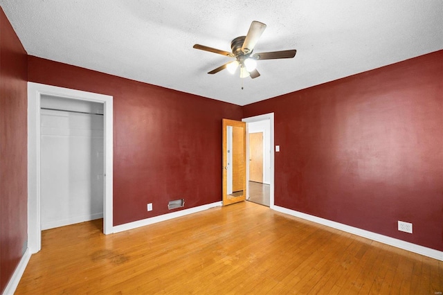 unfurnished bedroom featuring light wood-style flooring, a textured ceiling, baseboards, and ceiling fan