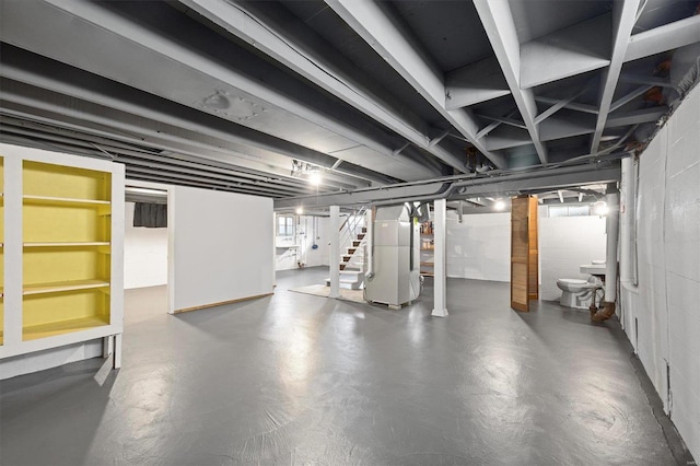 below grade area featuring stairs, concrete block wall, and heating unit