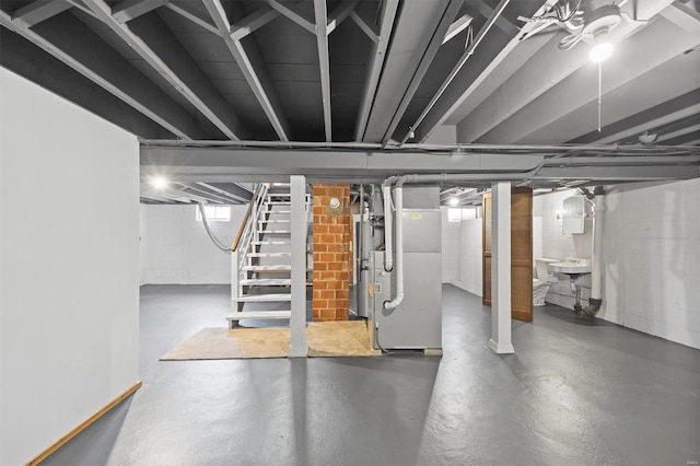 basement featuring stairs, heating unit, and water heater