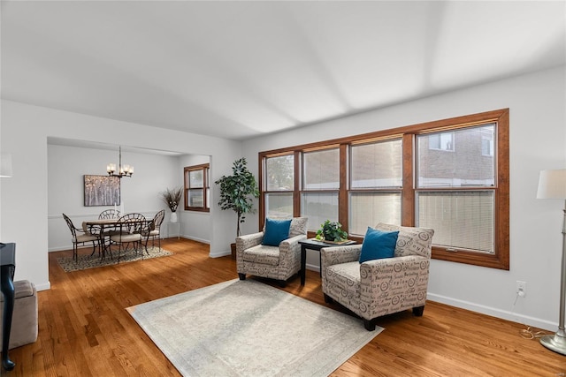 living area featuring baseboards, light wood-style floors, and a chandelier