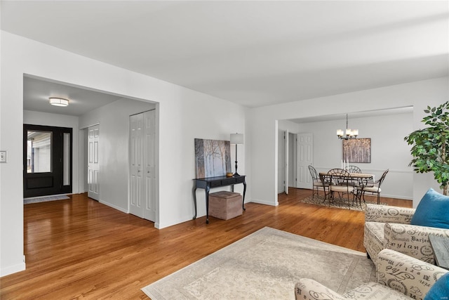 living area featuring baseboards, wood finished floors, and a chandelier