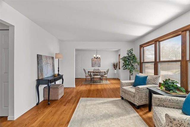 sitting room with a notable chandelier, baseboards, and light wood finished floors