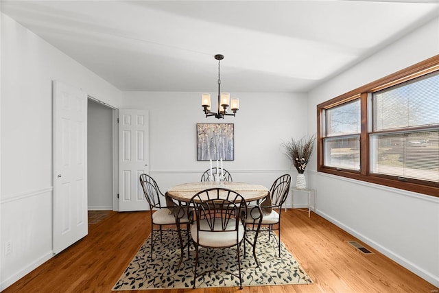 dining space featuring a chandelier, visible vents, light wood-style flooring, and baseboards