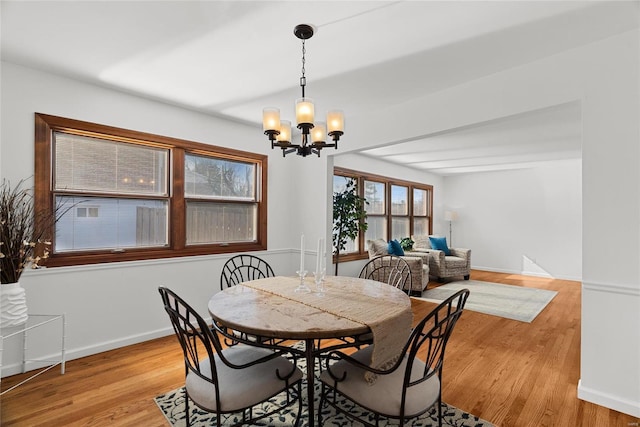 dining space featuring light wood-type flooring, baseboards, and a chandelier