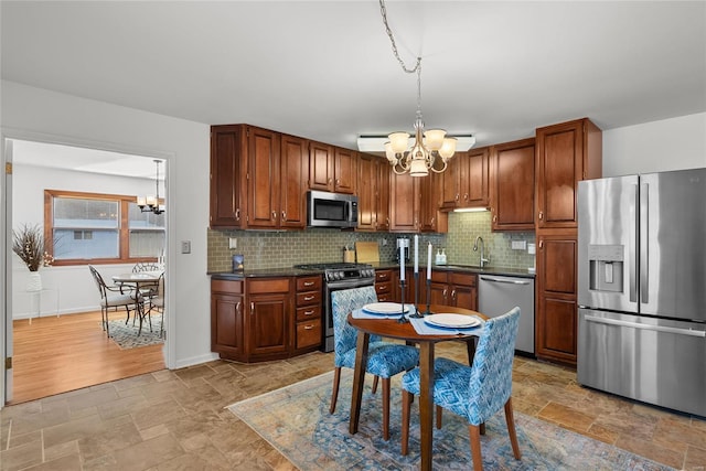 kitchen featuring stainless steel appliances, a notable chandelier, and dark countertops