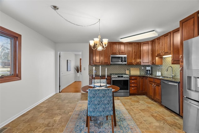 kitchen with backsplash, stone finish flooring, a notable chandelier, stainless steel appliances, and a sink