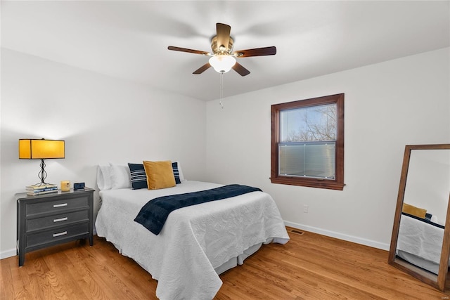 bedroom with light wood-type flooring, baseboards, and a ceiling fan