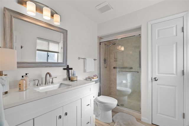 bathroom with visible vents, vanity, toilet, and a shower stall