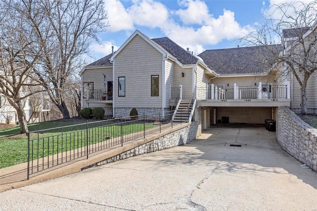 view of front of property featuring driveway, a shingled roof, stairs, a front lawn, and a fenced front yard