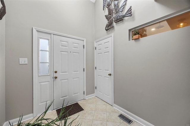 foyer entrance with light tile patterned floors, baseboards, and visible vents