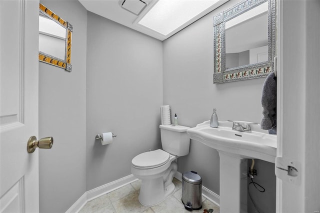 bathroom featuring tile patterned floors, toilet, baseboards, and a sink