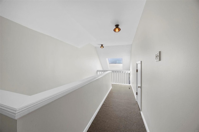 hall featuring vaulted ceiling with skylight, baseboards, and carpet