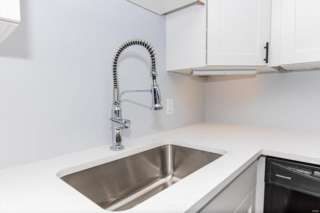 details featuring dishwasher, white cabinets, light stone counters, and a sink