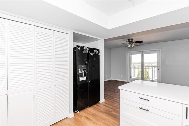 kitchen featuring light wood finished floors, light countertops, baseboards, ceiling fan, and black refrigerator with ice dispenser