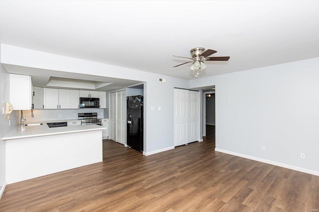 kitchen featuring dark wood-type flooring, baseboards, light countertops, black appliances, and a ceiling fan