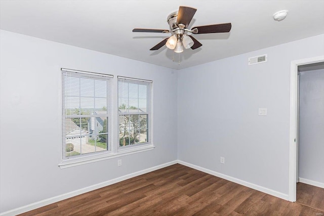 unfurnished room featuring visible vents, a ceiling fan, baseboards, and dark wood-style flooring