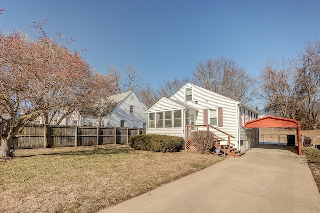 view of front of property with fence, concrete driveway, a front yard, a sunroom, and a carport