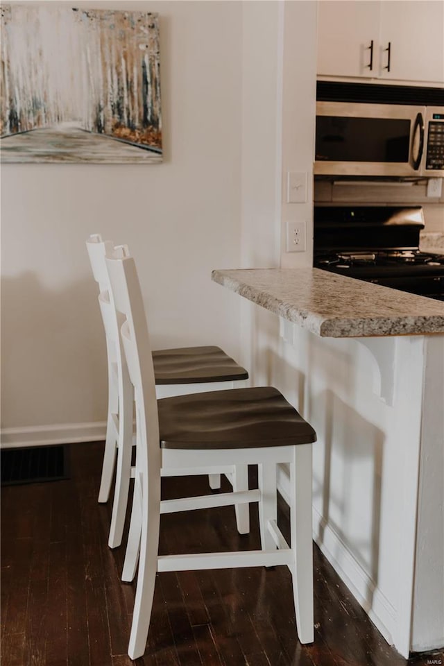 unfurnished dining area featuring baseboards and dark wood-style floors