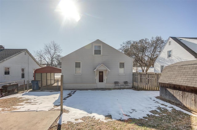 snow covered rear of property featuring an outdoor structure and fence