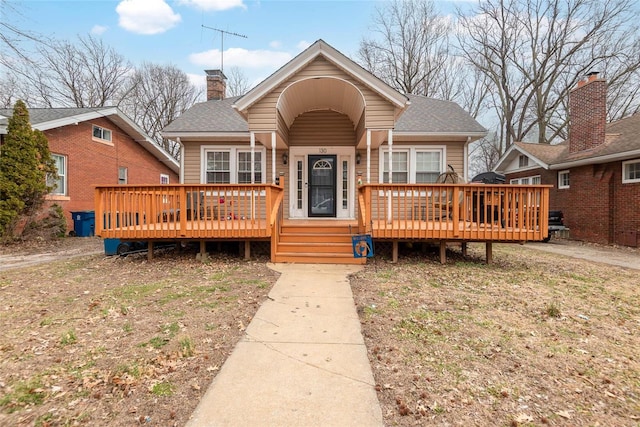 bungalow-style house with a wooden deck, a chimney, and a shingled roof