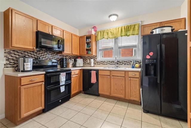 kitchen with decorative backsplash, black appliances, light countertops, and a sink