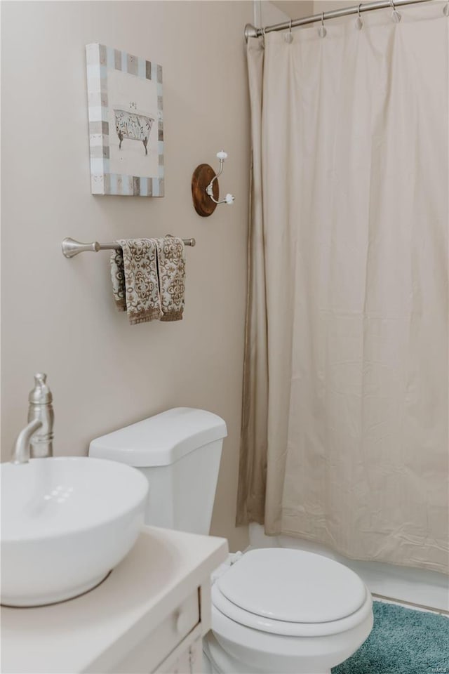 full bath with curtained shower, toilet, and a sink