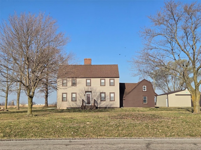 colonial inspired home with a front lawn, a chimney, and entry steps