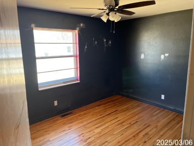 unfurnished room with visible vents, ceiling fan, and wood finished floors