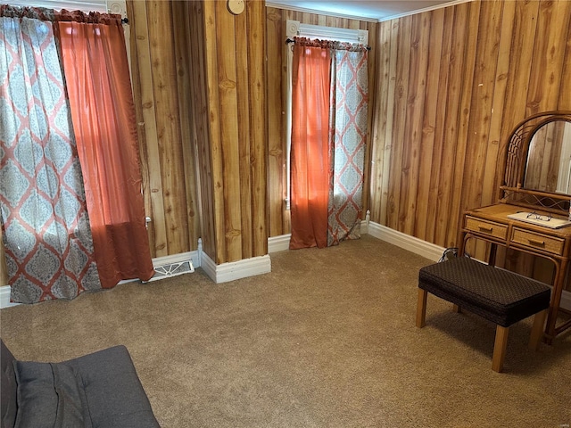 sitting room with visible vents, baseboards, wooden walls, and carpet flooring