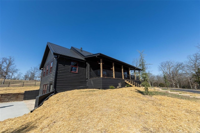 log cabin with metal roof, a porch, faux log siding, and stairway