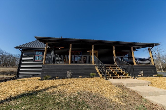 log cabin with log veneer siding, stairway, covered porch, and metal roof