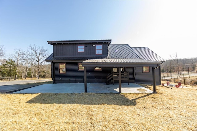 rear view of house featuring a patio area, fence, and metal roof