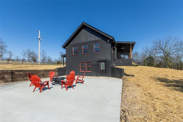 rear view of property featuring log veneer siding, a patio area, fence, and an outdoor fire pit