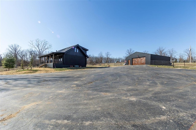 view of pole building featuring aphalt driveway and fence