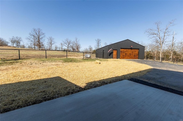 view of yard with fence, a pole building, driveway, an outdoor structure, and a detached garage