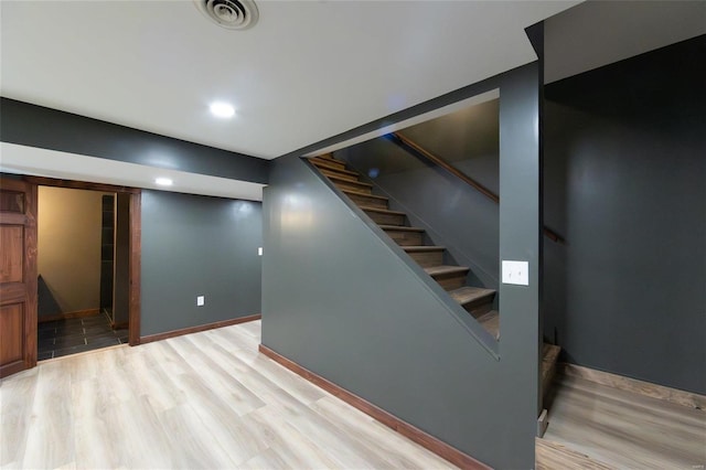 finished basement with visible vents, wood finished floors, recessed lighting, baseboards, and stairs