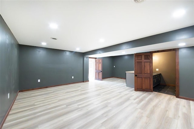 finished below grade area with recessed lighting, baseboards, and light wood-style flooring