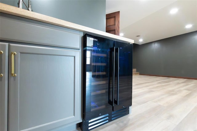 interior details with light countertops, light wood-style flooring, recessed lighting, and beverage cooler